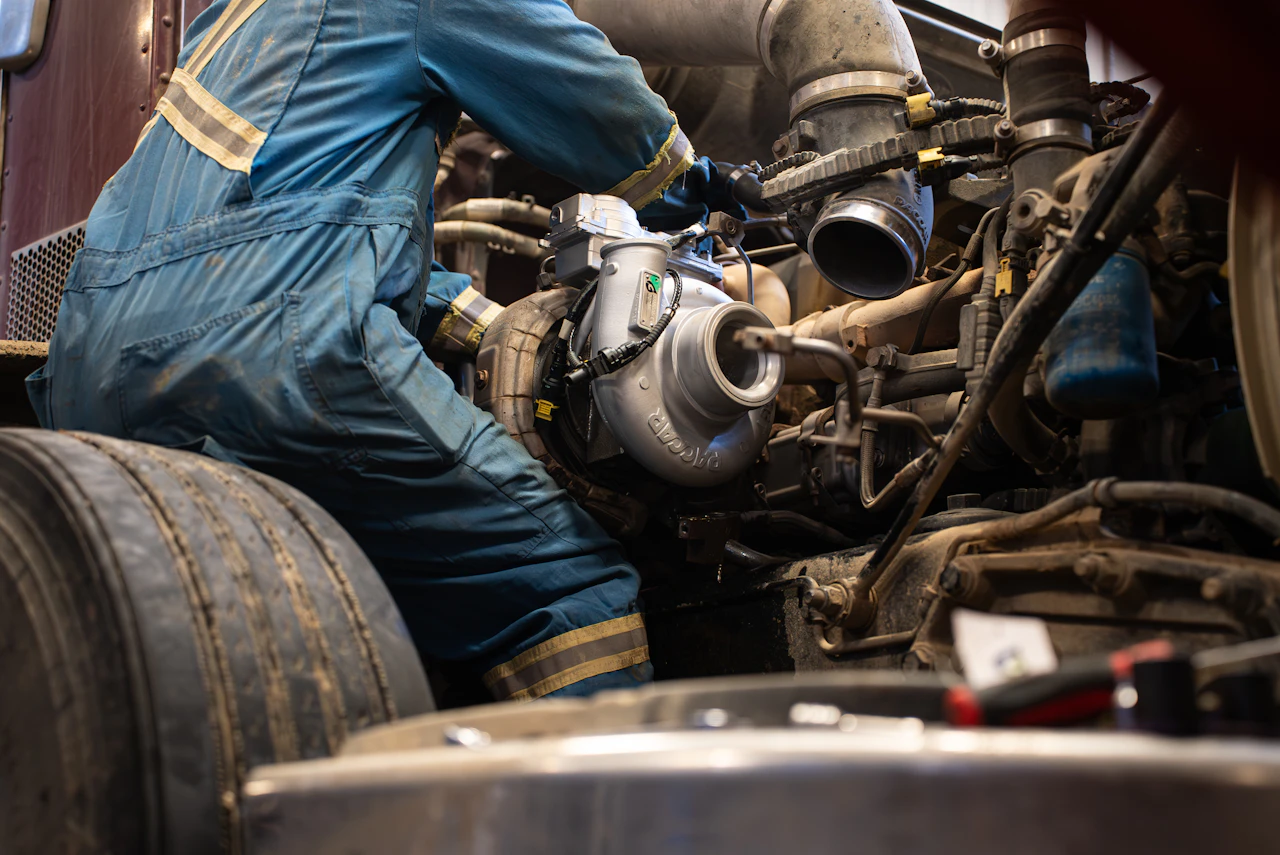 Turbocharger repair on a heavy-duty truck with technician installing a new turbo during engine service.